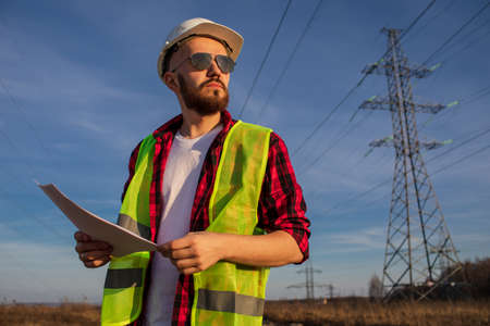Engineering working on high-voltage tower, check the information on paper at sunset backgroundの写真素材