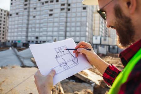 Engineering Consulting People on construction site holding blueprint in his hand. Building inspector