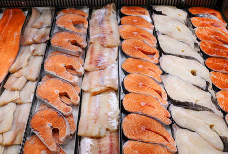 Sliced raw, not cooked fish, lying in the ice on the counter in the supermarket.