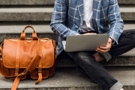 Stylish man using laptop computer on a street. Freelance work conceptの写真素材