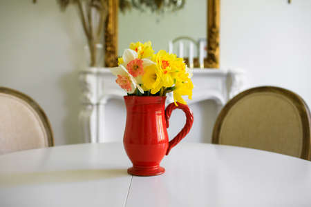 yellow narcissus in vase on white table. 