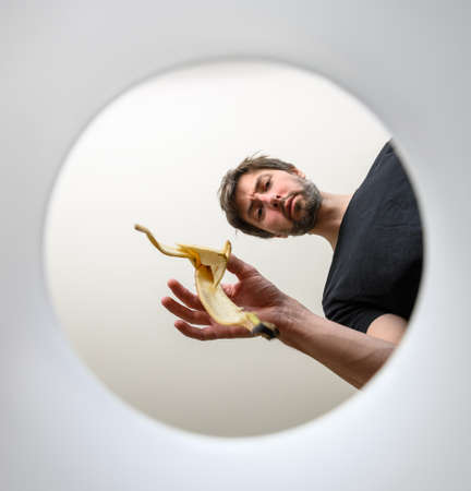 man throws garbage into a bucket. inside view. throws out a banana skinの写真素材