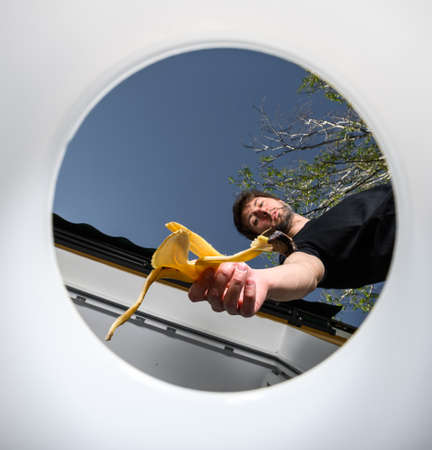 man throws garbage into a bucket. inside view. throws out a banana skin