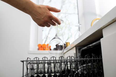 man puts dishes in the dishwasherの写真素材
