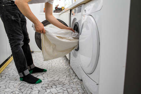 man puts laundry in an automatic washing machineの写真素材