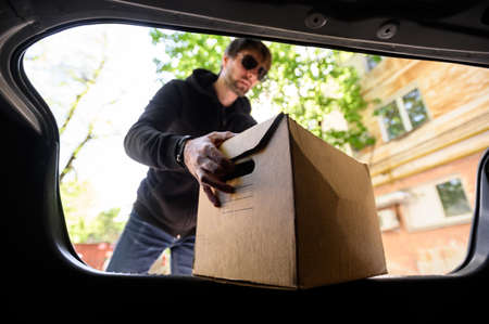 young man puts a box in the car