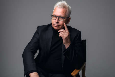 Close-up portrait of smiling middle aged businessman wearing eyewear while standing at isolated gray background.の写真素材