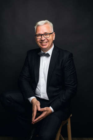 portrait of a middle-aged man with white hair wearing glasses in a business suitの写真素材