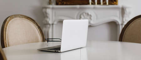 laptop on a white table in a beautiful bright room. Work from home. Remote trainingの写真素材