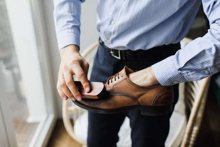 a man cleans shoes with a brush. Shoe cleaning from dirtの写真素材