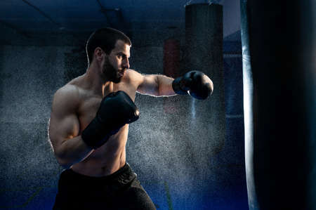 Powerful male boxer with punching bag for uppercut trainingの写真素材