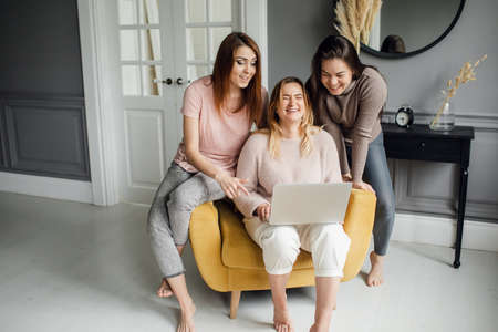 a group of girlfriends communicate with a friend via a video conference on a laptop. Friendshipの写真素材