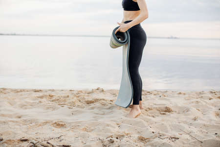 sports girl doing yoga on the beach. Girl with exercise mat
