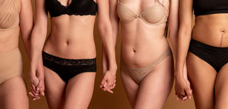 friendship, beauty, body positive and people concept - group of happy women different in underwear over gray backgroundの写真素材