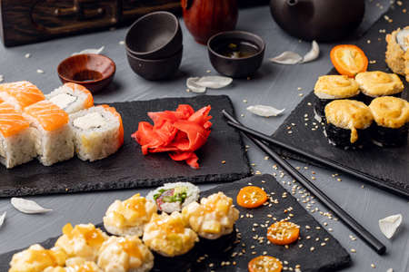 Sushi rolls, sashimi set, miso soup and teapot, on dark wooden table, Japanese food, top view.の写真素材