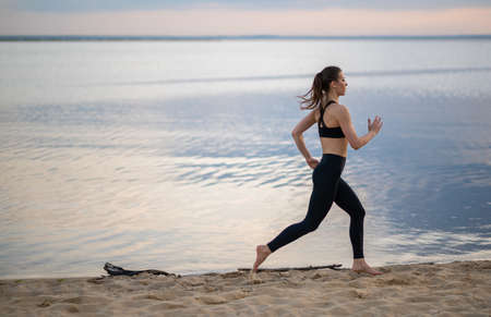 fitness and lifestyle concept - woman doing sports outdoors on a beachの写真素材
