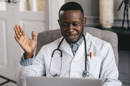black doctor Using Laptop To Communicate with a patient. Smiling male african american professional...