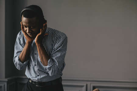 Young african man listening to music with wireless earphones and dancing at homeの写真素材