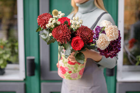 people, business, sale and floristry concept - close up of florist woman holding bunch at flower shopの写真素材