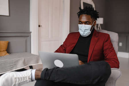 a black man works at a laptop close-up of his face. video conferences man wearing medical maskの写真素材