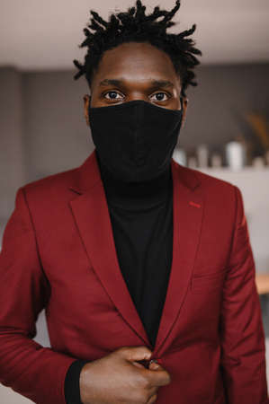 portrait of an afro american in a suit wears a black medical mask