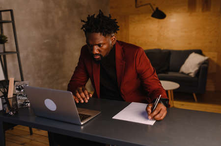 black business man working on laptop and taking notes