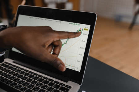 Black Businessman using laptop for analyzing data stock market, forex trading graph, stock exchange trading online, financial investment concept. close upの写真素材