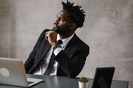 Confident young african man look at webcam conference video calling in office, happy mixed race entrepreneur talking doing online video chat job interview sit at deskの写真素材