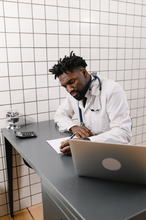 Handsome contented African American doctor working on a laptop. telemedicineの写真素材