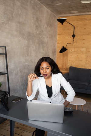 Portrait of a pretty cheerful black business woman sitting in a modern office. Positive thinking...