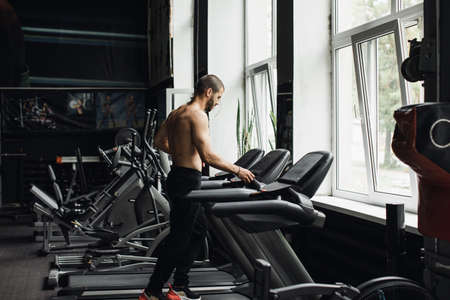Man running in a gym on a treadmill concept for exercising, fitness and healthy lifestyle