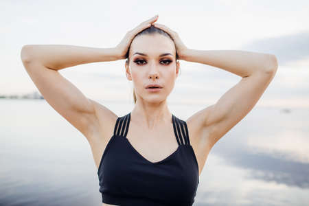 athletic girl with tank top doing a stretch on the beachの写真素材