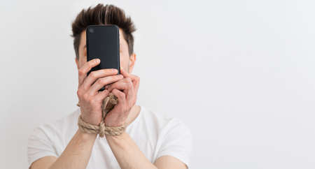 internet addiction or social media addiction. Hands tied with a rope hold a smartphone