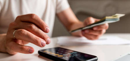 accounting, taxes and finances concept. Man with papers and calculator counting money at home, the concept of counting money accounting, taxes and finances concept.の写真素材