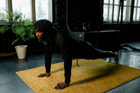 african american man doing push-ups in modern gym with large windows