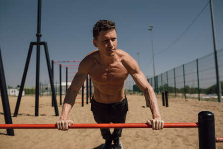 Young Man Doing Calisthenics Outdoors. Man Doing Pull-Ups in the Street. Guy Working Out on Pull-Up...