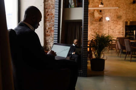 a young aspiring African-American investor works at a computer, analyzes the securities market