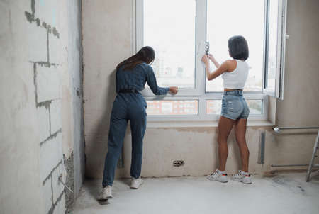 Renovation apartment. A beautiful smiling woman makes repairs in her apartment. Empty walls, repairs house with their own hands.の写真素材