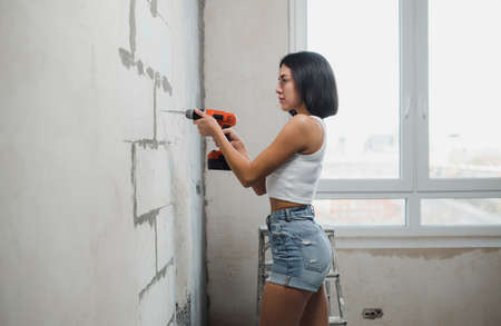 A young woman makes apartment renovations. Apartment renovation concept. Strong independent womanの写真素材