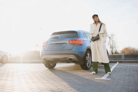 young stylish girl and her new car in the parking