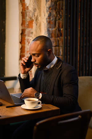 African-American man is working at a laptop in a cafe. Free work schedule, freelancer