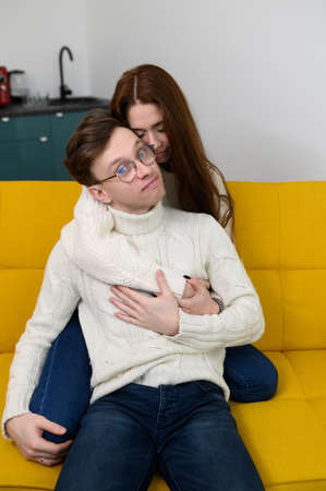 a young couple spend time at home together. Fooling around sitting on the couch. A man tries on a...