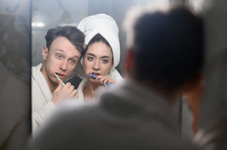 a young married couple brushing their teeth together. Dental hygiene.の写真素材