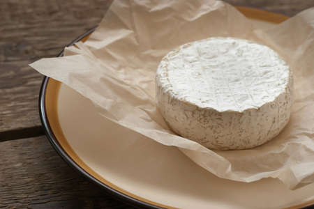Whole camembert cheese on the white parchmentの写真素材
