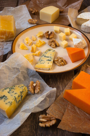 Assorted cheeses on the wooden table (sbrinz, camembert, cheddar, blueshatel,)の写真素材