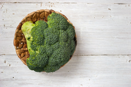Broccoli in the basket on the white wooden table horizontalの写真素材