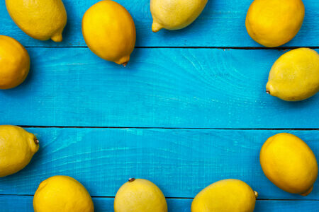 Yellow colorful lemons on the bright cyan wooden table horizontalの写真素材