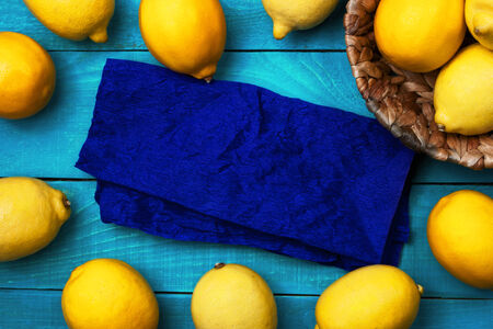 Yellow colorful lemons and the blue serviette on the bright cyan wooden table horizontalの写真素材