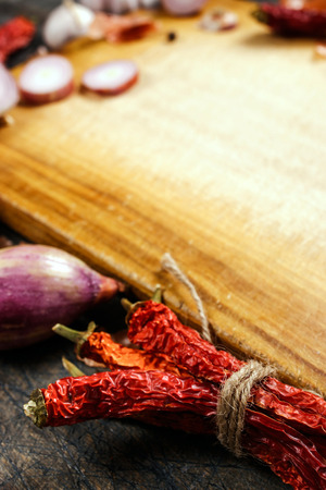 Wooden board with onions, garlic and pepper background verticalの写真素材