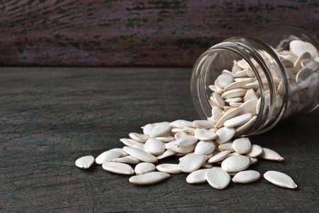 Pumpkin seeds in the glass jar on the rustic wooden table